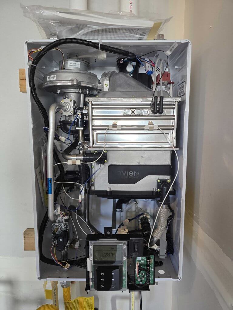 Interior view of a gas tankless water heater showing internal components such as the heat exchanger, gas burner, and wiring.